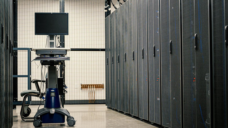 Contemporary computer on support between telecommunication racks and cabinets in modern data center
